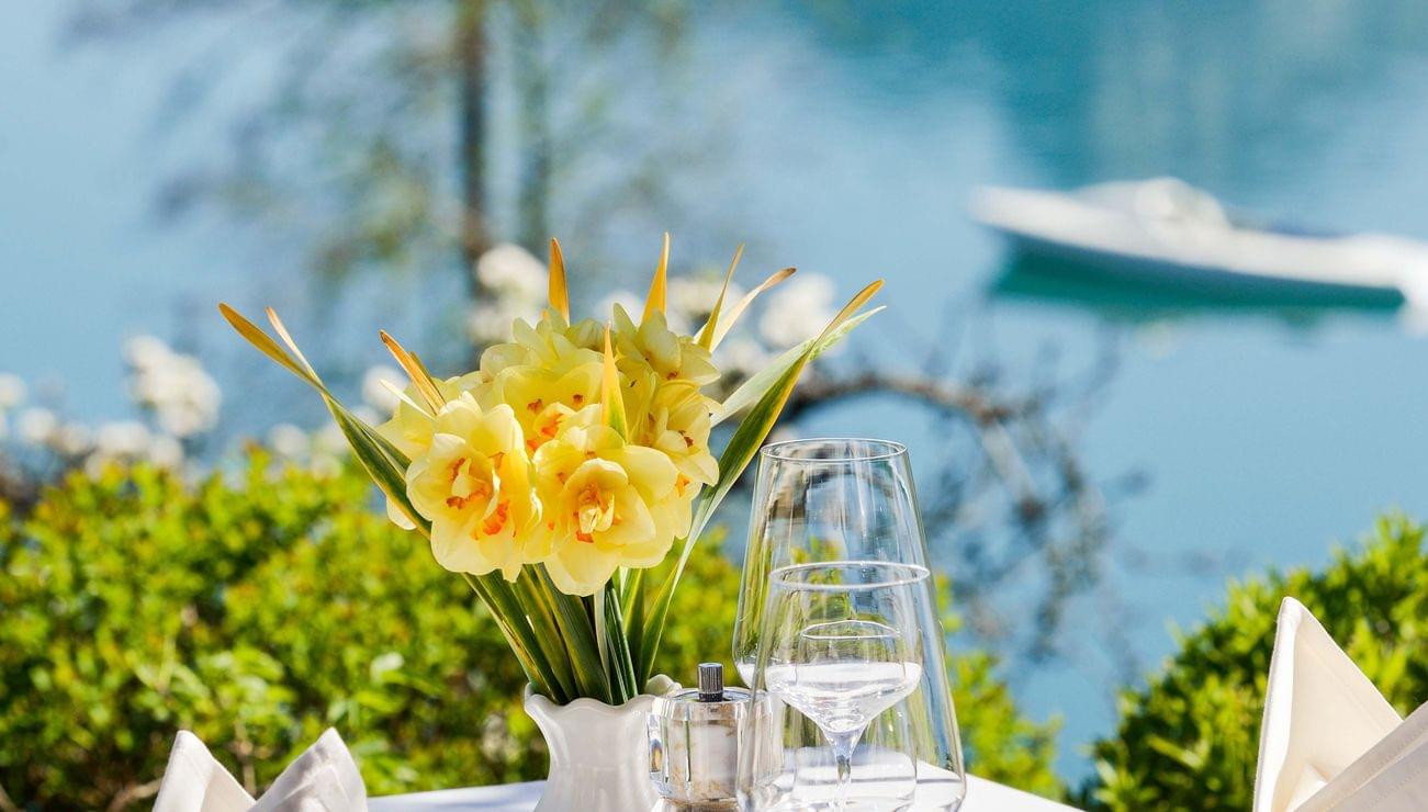 Elegante tavola all'aperto apparecchiata con fiori e vista lago