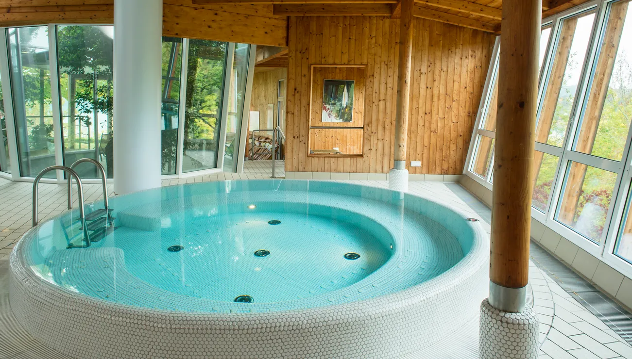 Innenwhirlpool im Spa mit rundem Becken und Holzwänden umgeben von großen Fenstern