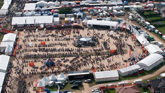 Luftaufnahme einer Motorradveranstaltung mit geparkten Bikes, Zelten und großer Menschenmenge