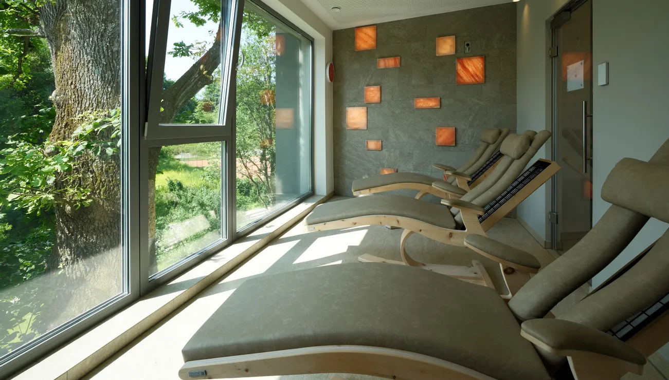 Ruheraum mit ergonomischen Liegestühlen und großem Fenster mit Blick auf Bäume