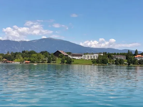 Seeufer-Resort mit Bergkulisse unter blauem Sommerhimmel
