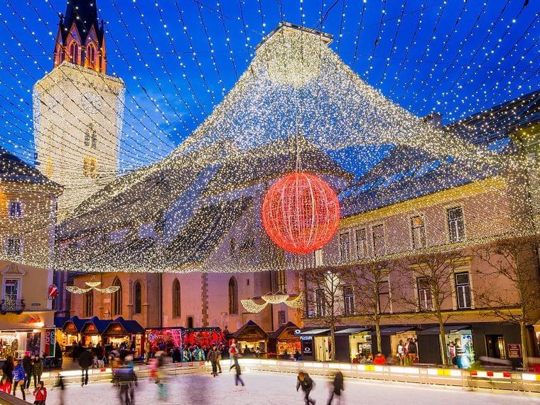 Mercatino di Natale con pista di pattinaggio e luci festive in una piazza storica