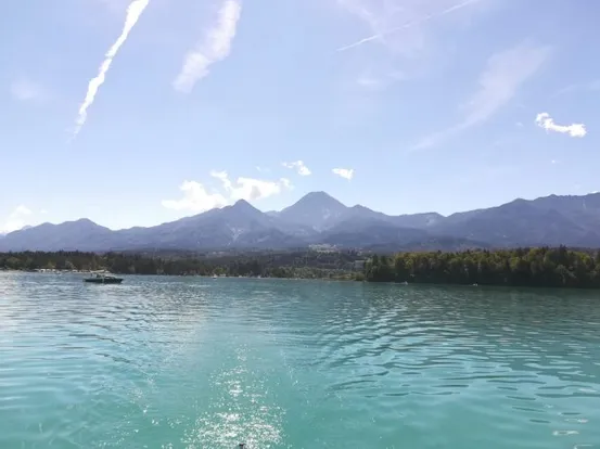 Klarer türkisfarbener See mit Bergkette und blauem Himmel im Hintergrund