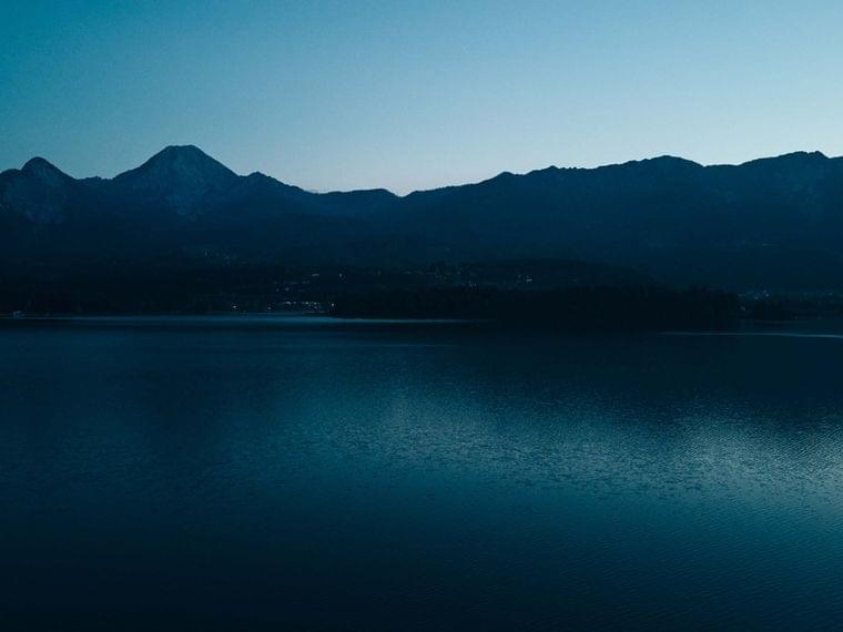 Bergsilhouette in der Dämmerung spiegelt sich im ruhigen See