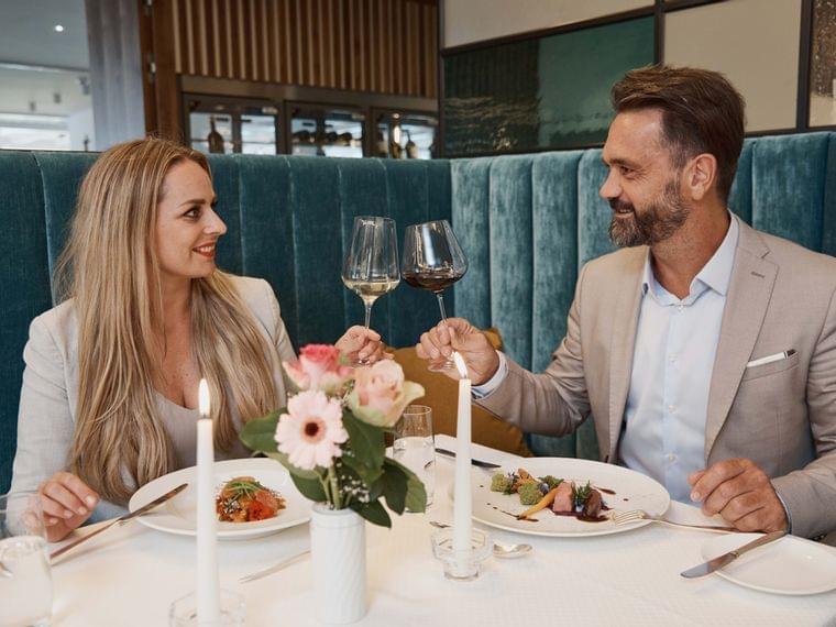 Elegantes Paar stößt mit Wein im romantischen Gourmetrestaurant an