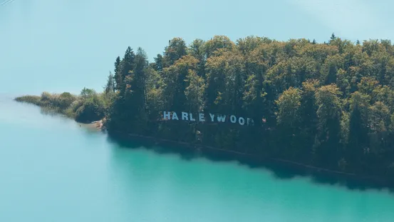 Waldinsel mit HARLEYWOOD-Schriftzug an einem türkisfarbenen See