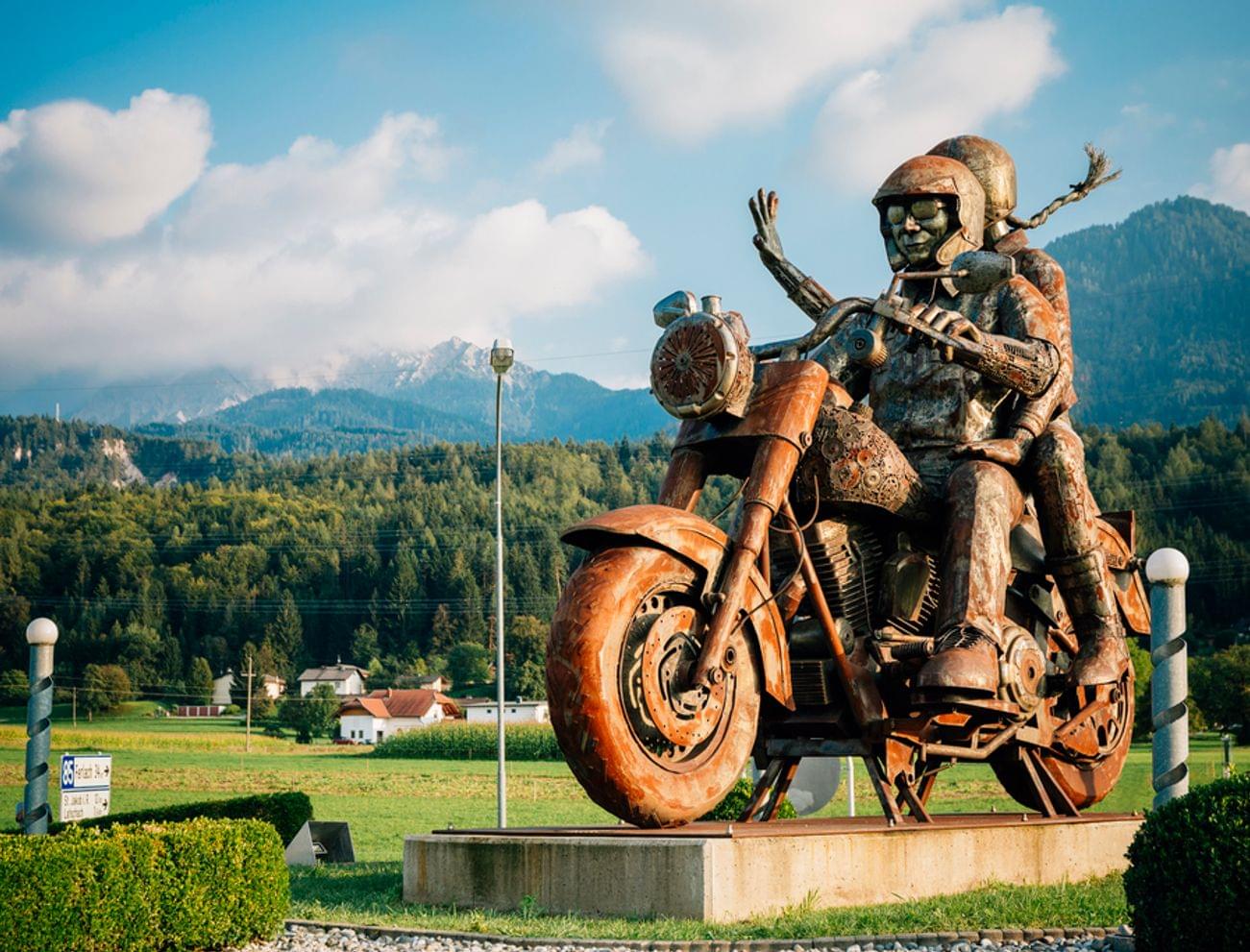 Rostige Metalls Skulptur von zwei Motorradfahrern vor Bergkulisse