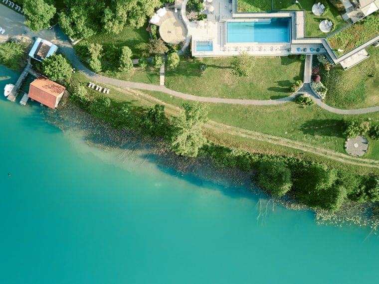 Vista aerea di un resort sul lago con piscina, molo, prato verde e acqua turchese