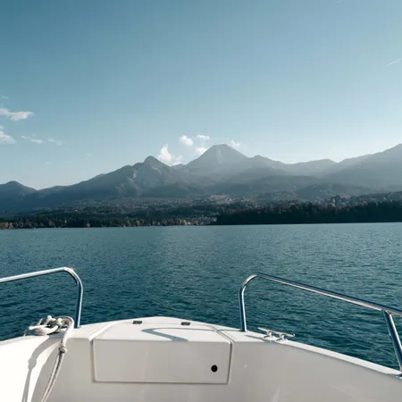 Vista di montagne e lago dal ponte di una barca sotto cielo azzurro