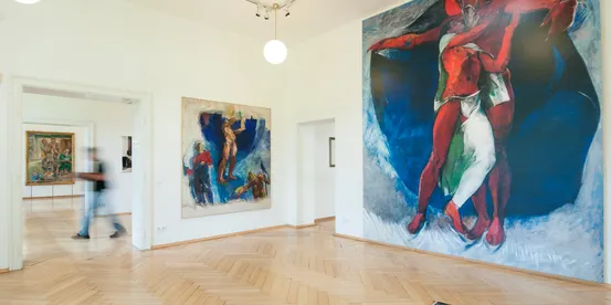 Modern art gallery with large colorful figurative paintings on white walls and wooden floor