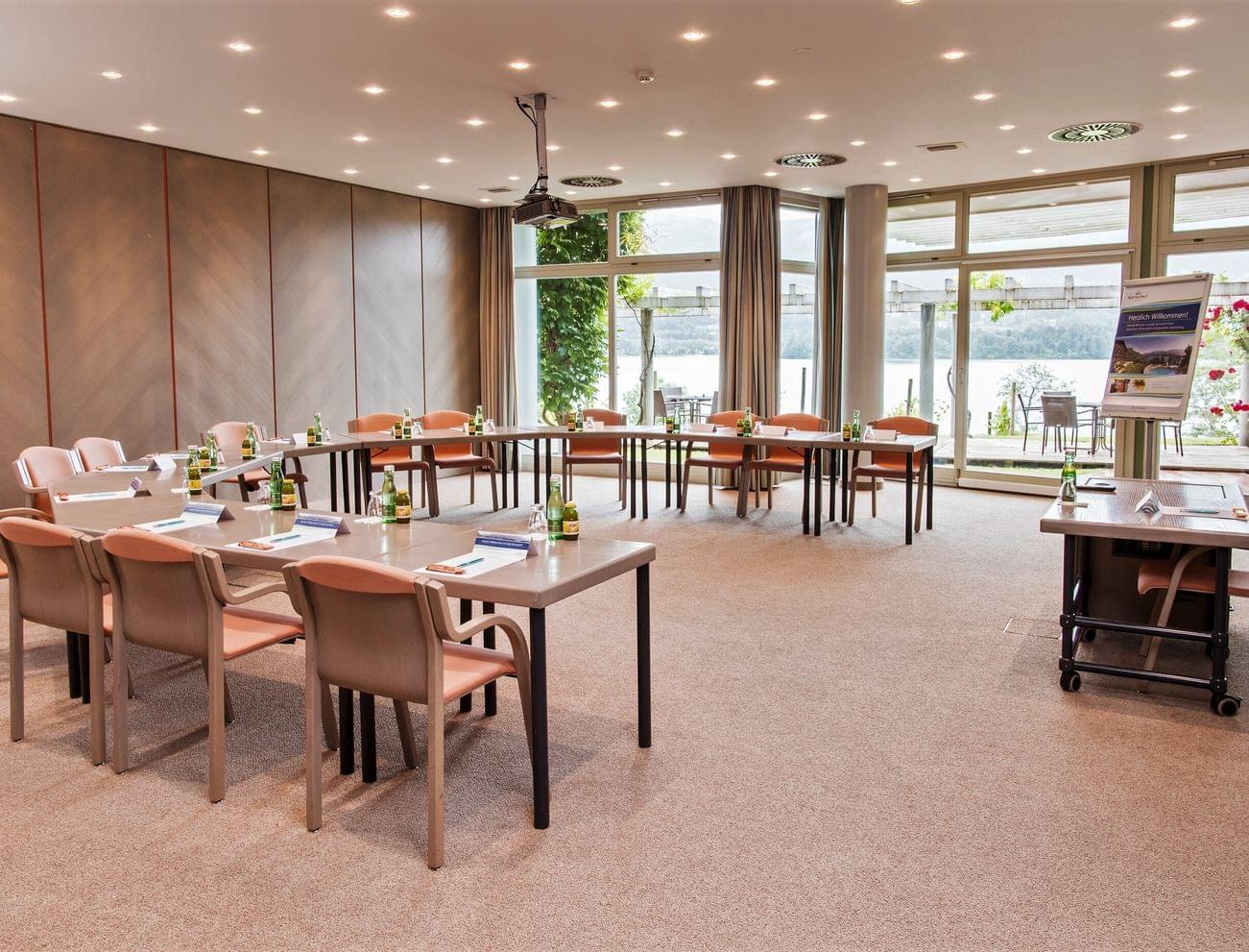 Moderner Konferenzraum mit U-förmiger Tischanordnung und Seeblick durch große Fenster