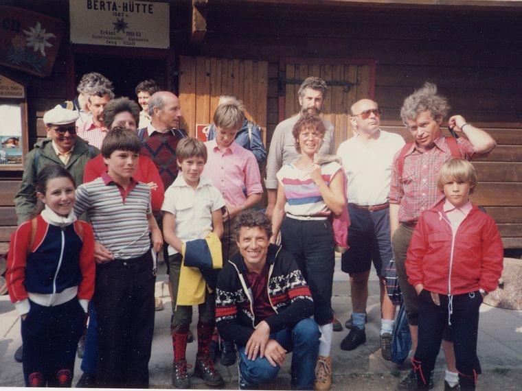Group of hikers posing outside Berta Hut in casual outdoor clothing