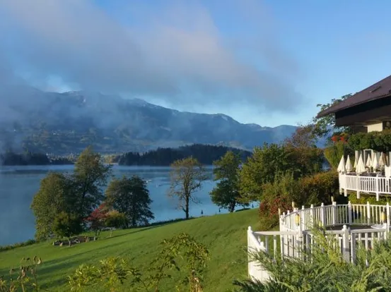 Hotelterrasse am See mit Bergblick und Morgennebel über stillem Wasser