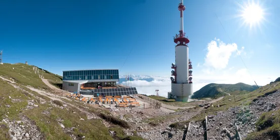 Berggipfelstation mit Alpenrestaurant, Solarpaneelen und hohem Sendeturm bei klarem Himmel