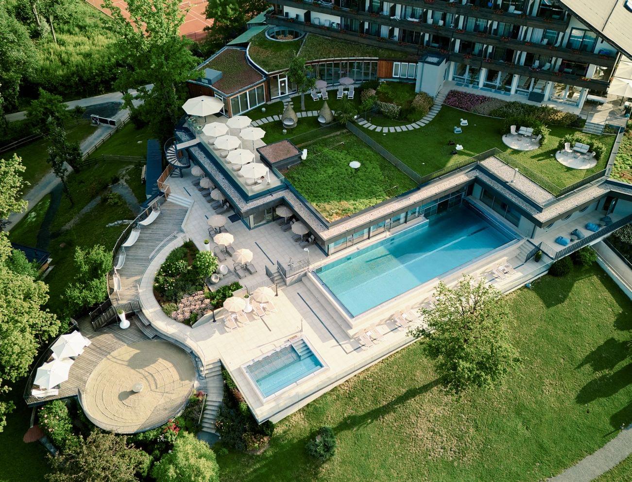 Luxury wellness hotel with outdoor pool, garden terraces and green rooftop in lush surroundings