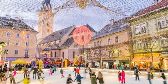 People ice skating at a festive Christmas market with lights and historical buildings