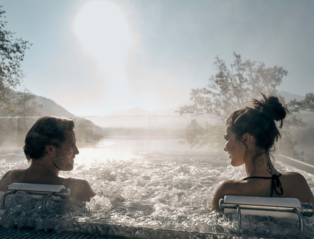Paar entspannt im Außen-Whirlpool mit Bergblick und Morgensonne