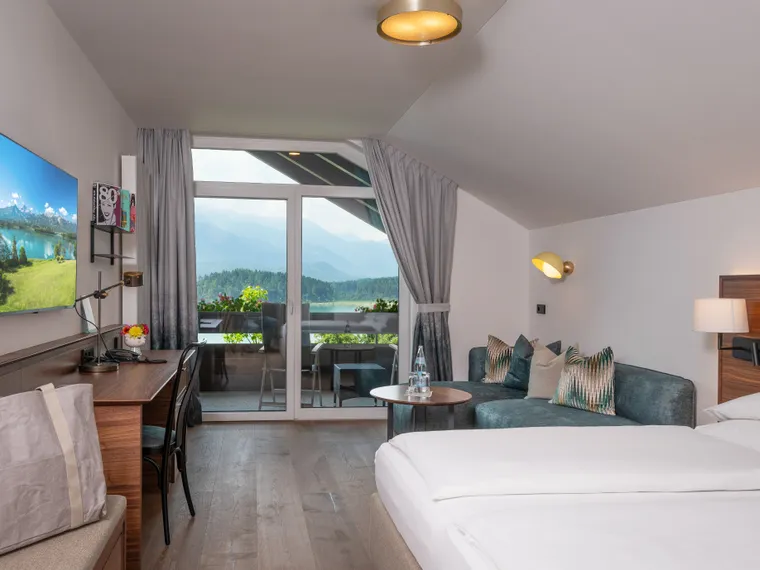 Modernes Hotelzimmer mit Balkon und Bergblick, Schreibtisch, Fernseher und gemütlicher Sitzecke
