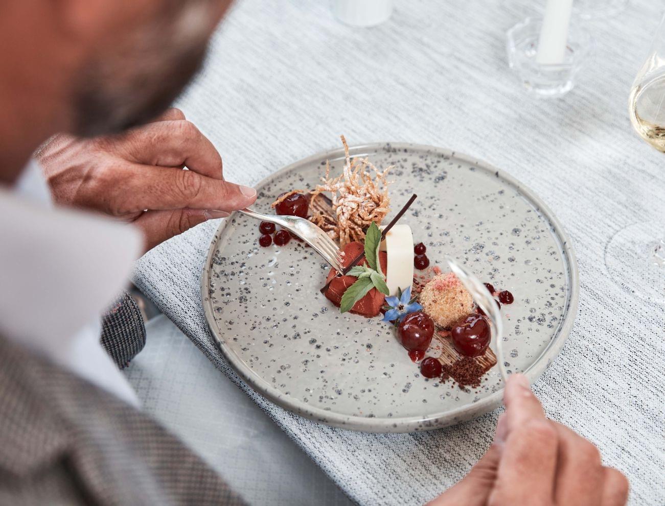 Gourmet dessert with cherries, mousse and edible flowers on speckled plate
