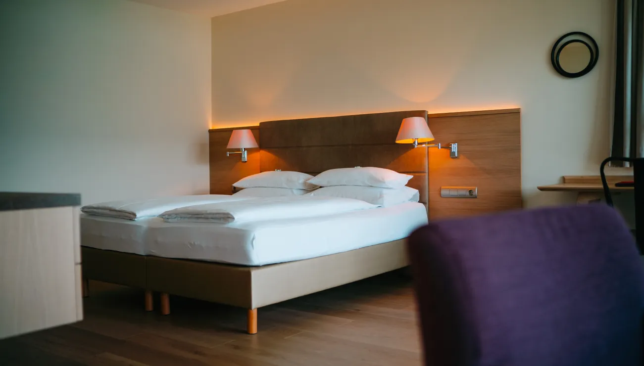 Modernes Hotelzimmer mit Doppelbett, Holzboden und stimmungsvollem Wandlicht
