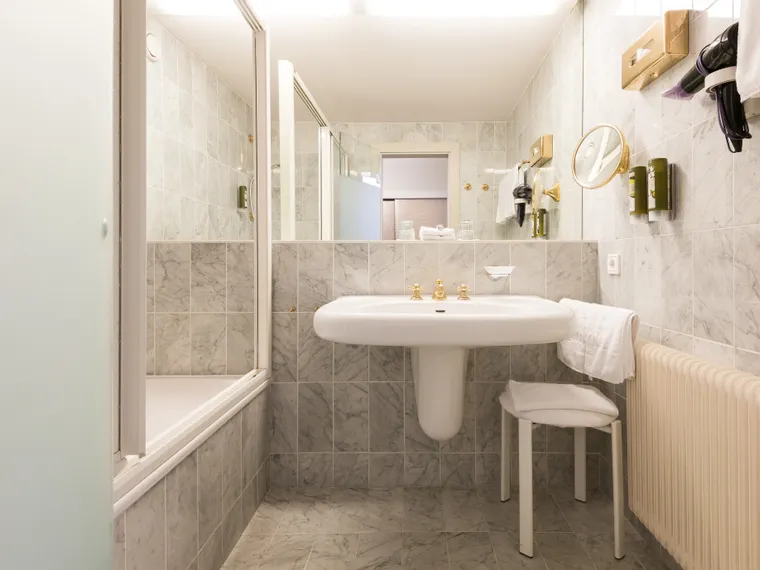 Elegantes Hotelbad mit Marmorkacheln, Badewanne, Waschbecken und montierten Annehmlichkeiten