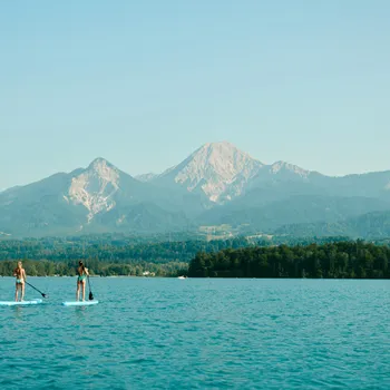 Due persone fanno paddleboard su un lago con montagne sullo sfondo