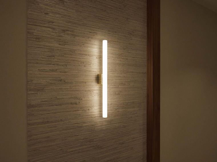 Moderne vertikale Wandleuchte mit warmem LED-Licht an strukturierter beiger Wand