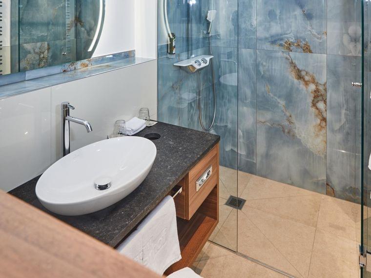 Modernes Badezimmer mit Aufsatzwaschbecken, Glasdusche, Holzwaschtisch und blauen Marmorfliesen