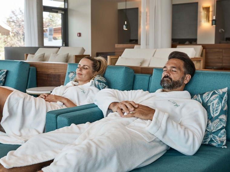Couple relaxing in spa lounge chairs wearing white bathrobes