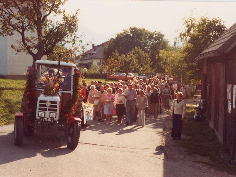 Harvest festival parade with decorated tractor and crowd walking through village street