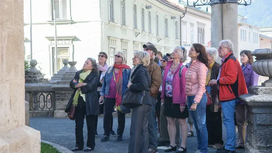 Reisegruppe hört einem Stadtführer in einer europäischen Altstadt mit historischen Gebäuden zu