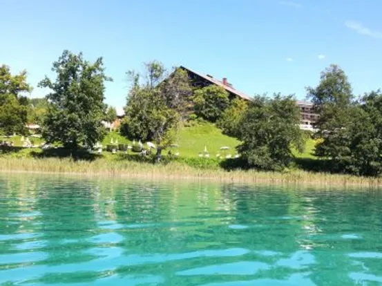 Seeufer-Resort mit türkisfarbenem Wasser, grüner Wiese und Bäumen unter klarem Himmel