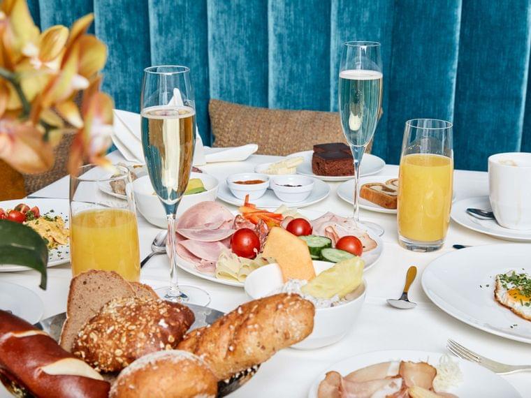 Elegant breakfast table with bread, cold cuts, cheese, fruit, eggs, juice, and champagne