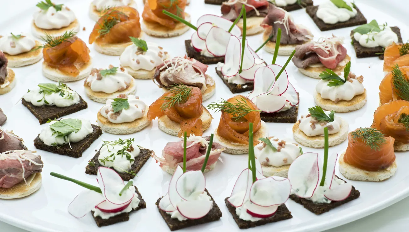 Verschiedene Gourmet-Canapés mit Räucherlachs, Radieschen, Roastbeef und Creme auf Roggen- und Weißbrot
