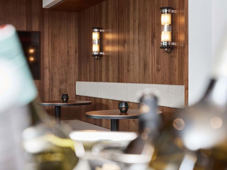 Modern restaurant seating area with round wooden tables and wall-mounted lights