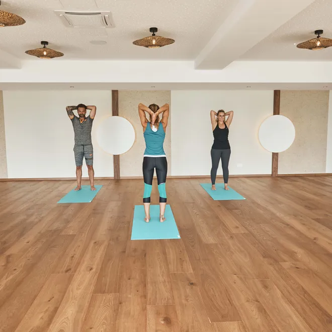 Fitnessgruppe übt Yoga-Positionen auf Matten in einem geräumigen Studio
