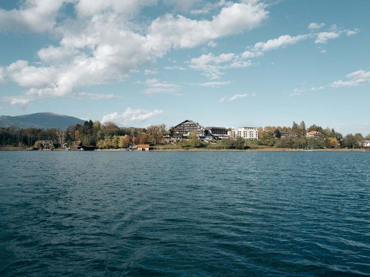 Seeufer-Resort mit Bergen im Hintergrund unter teils bewölktem Himmel
