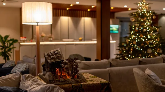 Gemütliche Hotellobby mit Weihnachtsbaum, Tischlampe und Krippendekoration