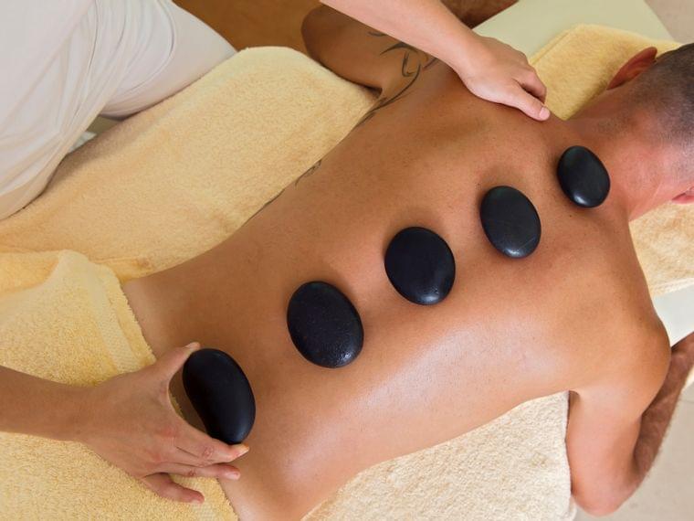Mann erhält Hot-Stone-Massage im Wellnessbereich