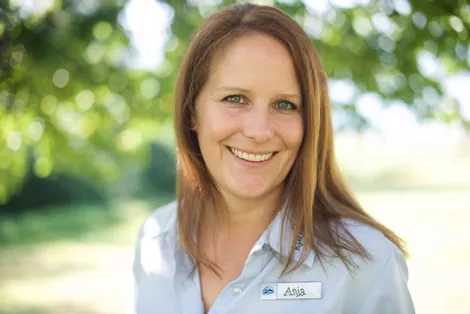 Smiling woman with name tag Anja standing outdoors in soft natural light