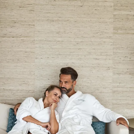 Couple relaxing in white spa robes on a sofa at a wellness resort