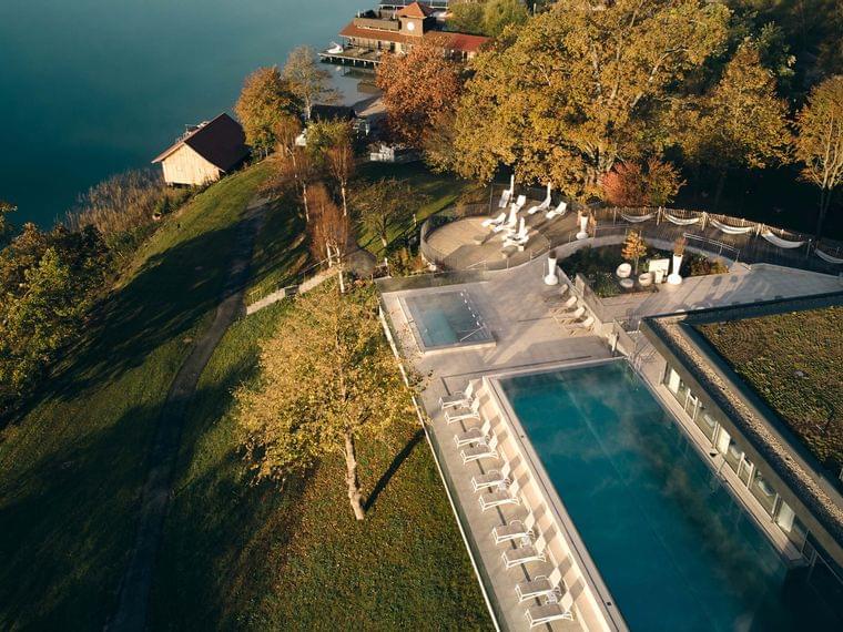 Resort di lusso sul lago con piscina all'aperto, lettini prendisole e bosco autunnale