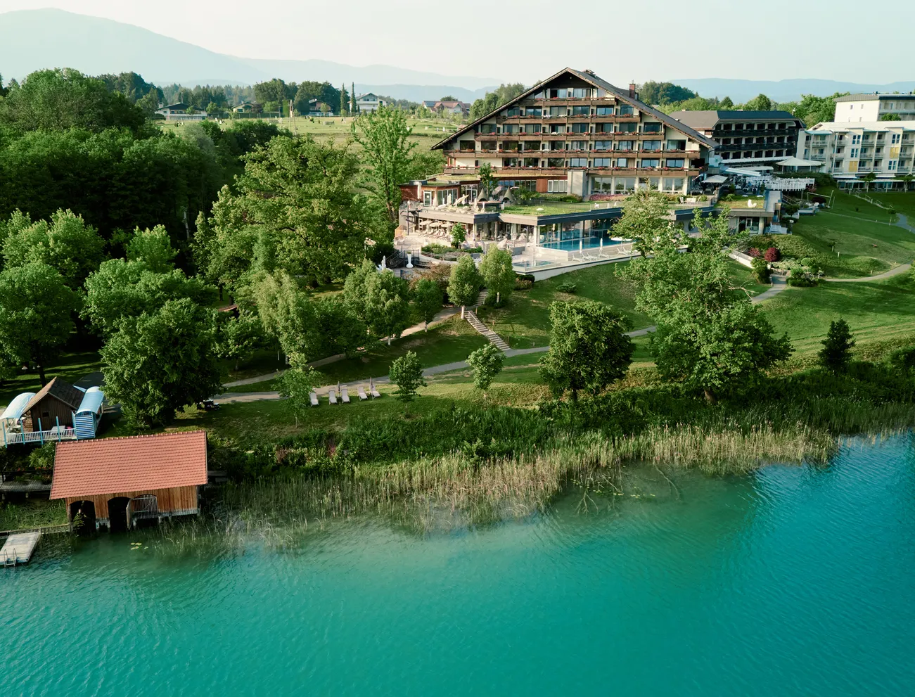 Luxuriöses Hotel am See, umgeben von Wald und Bergen mit privatem Steg am türkisfarbenen Wasser