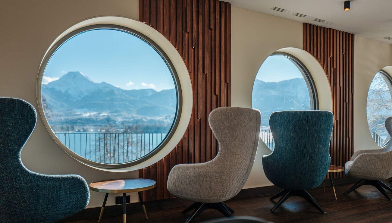 Poltrone moderne rivolte verso finestroni rotondi con vista sulle montagne in hotel di lusso