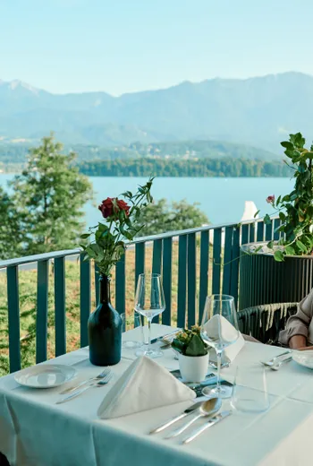 Donna che cena su un balcone con vista sul lago e sulle montagne