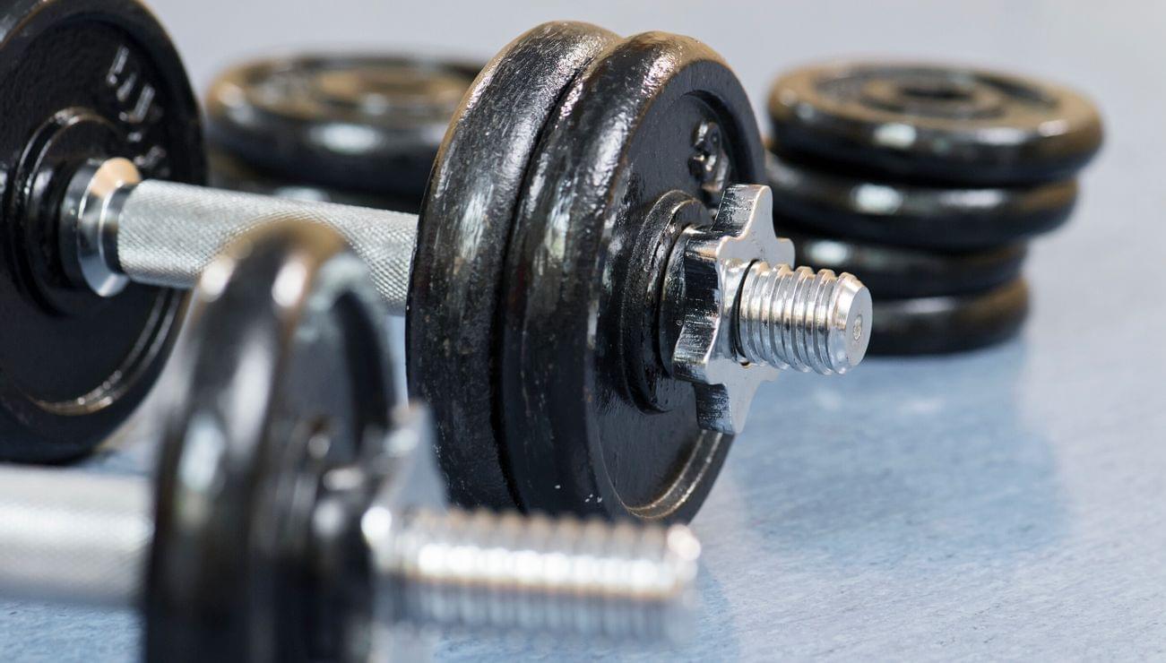 Close-up of adjustable dumbbells with metal weight plates on gym floor
