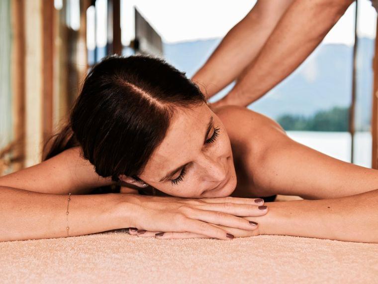 Entspannte Frau erhält Rückenmassage im Spa mit Bergblick