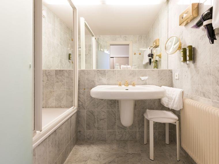 Elegante bagno d'hotel con piastrelle in marmo, vasca, lavandino e accessori montati