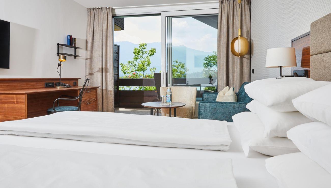 Modernes Hotelzimmer mit Bergblick, Schreibtisch, Bett und Balkon-Sitzbereich