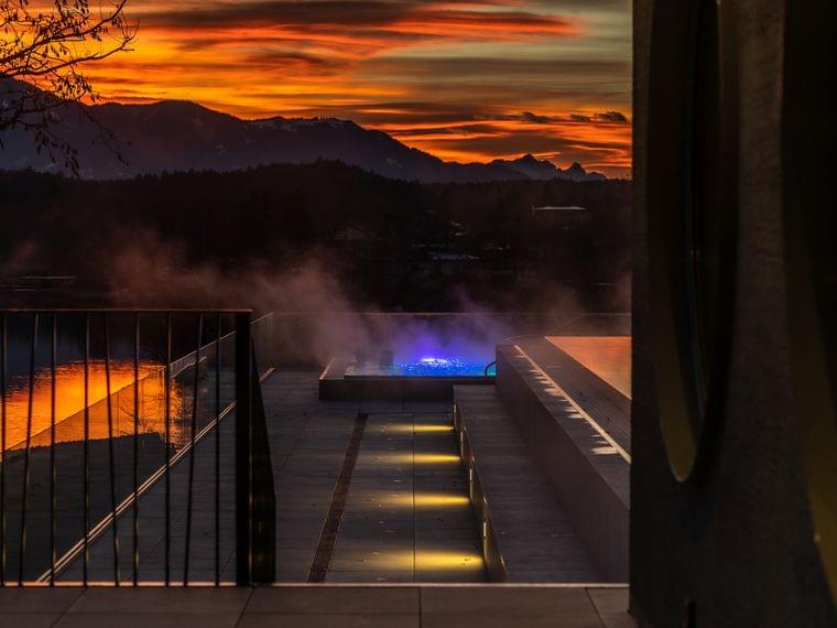Luxus-Spa-Infinity-Pool bei Sonnenuntergang mit Bergblick und aufsteigendem Dampf